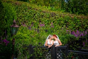 A romantic couple's moment on a garden balcony surrounded by purple flowers and lush greenery.