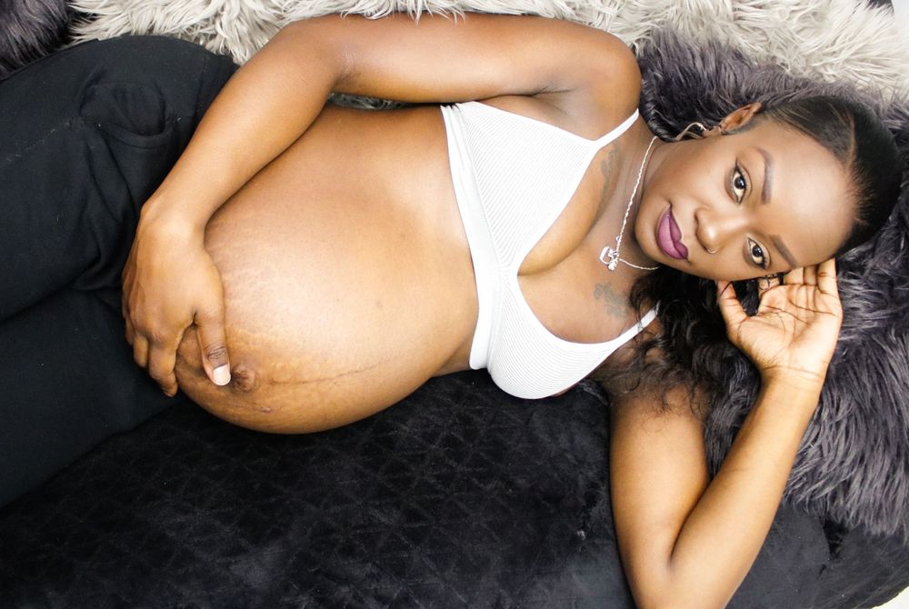 Maternity photoshoot on black fur backdrop in artistic style.