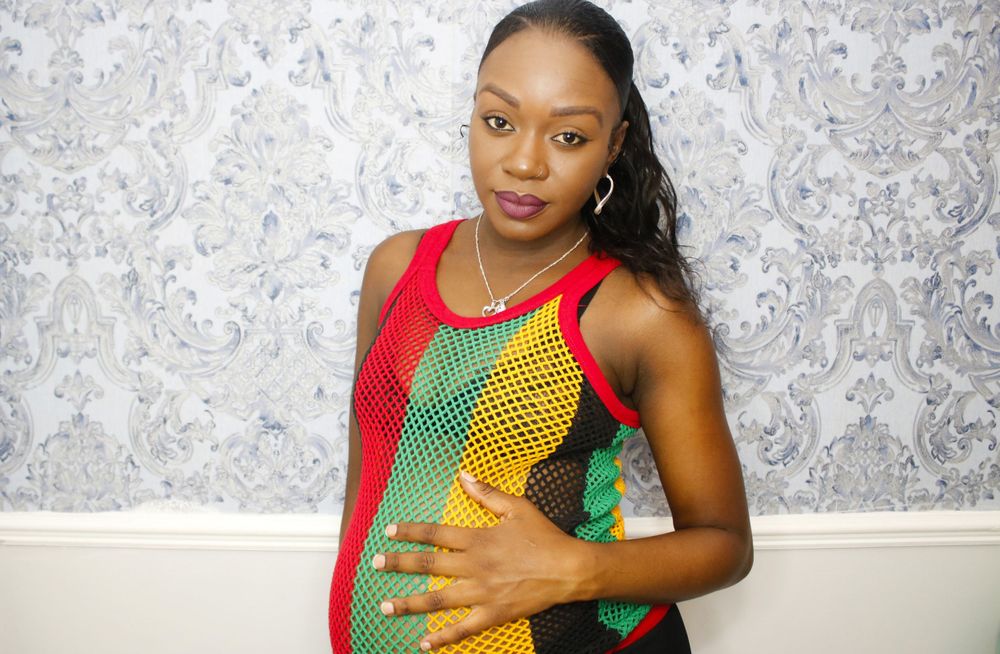 Maternity photo featuring traditional African-inspired red, yellow and green clothing.