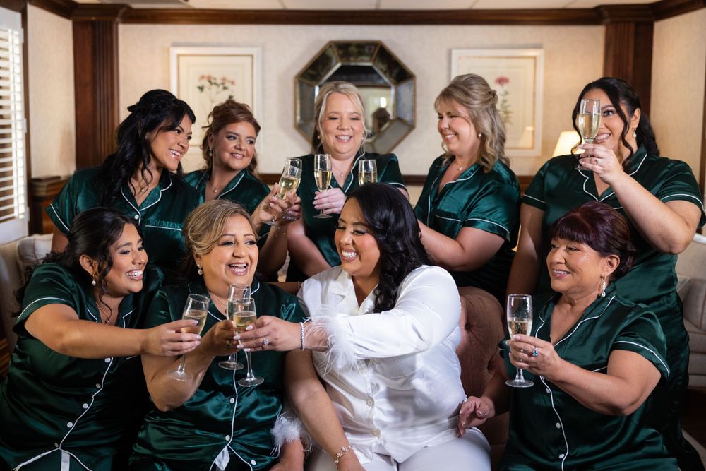 Wedding party in matching green dresses celebrating with champagne glasses.