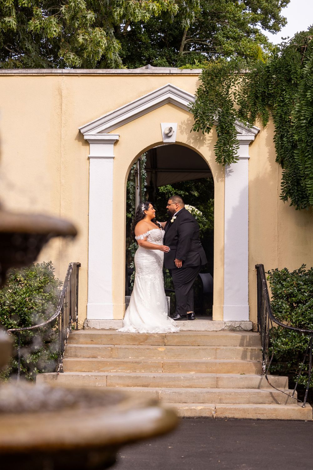 Couple sharing intimate moment in arched doorway during wedding photoshoot.