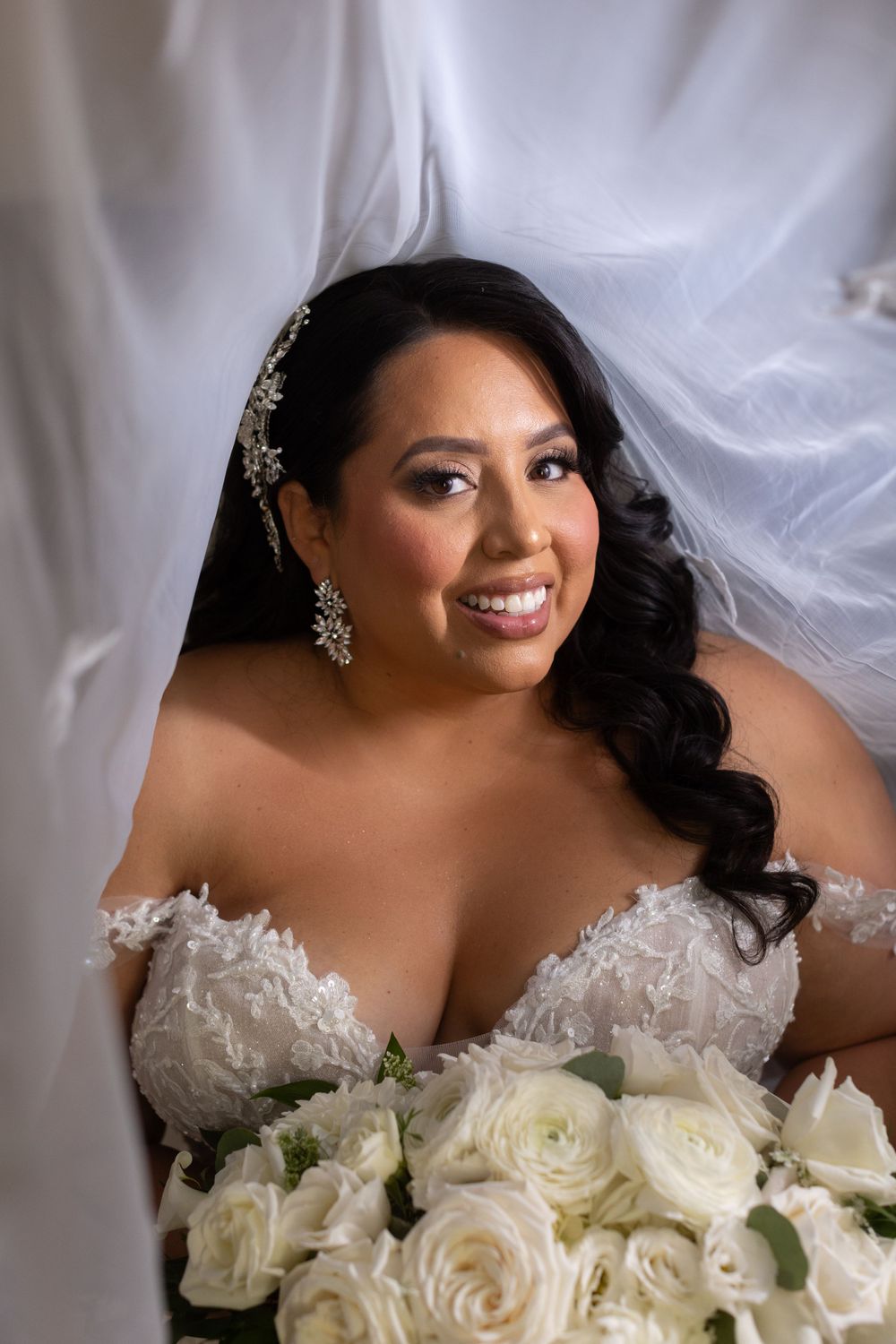 Close-up bridal portrait with white roses and elegant veil.