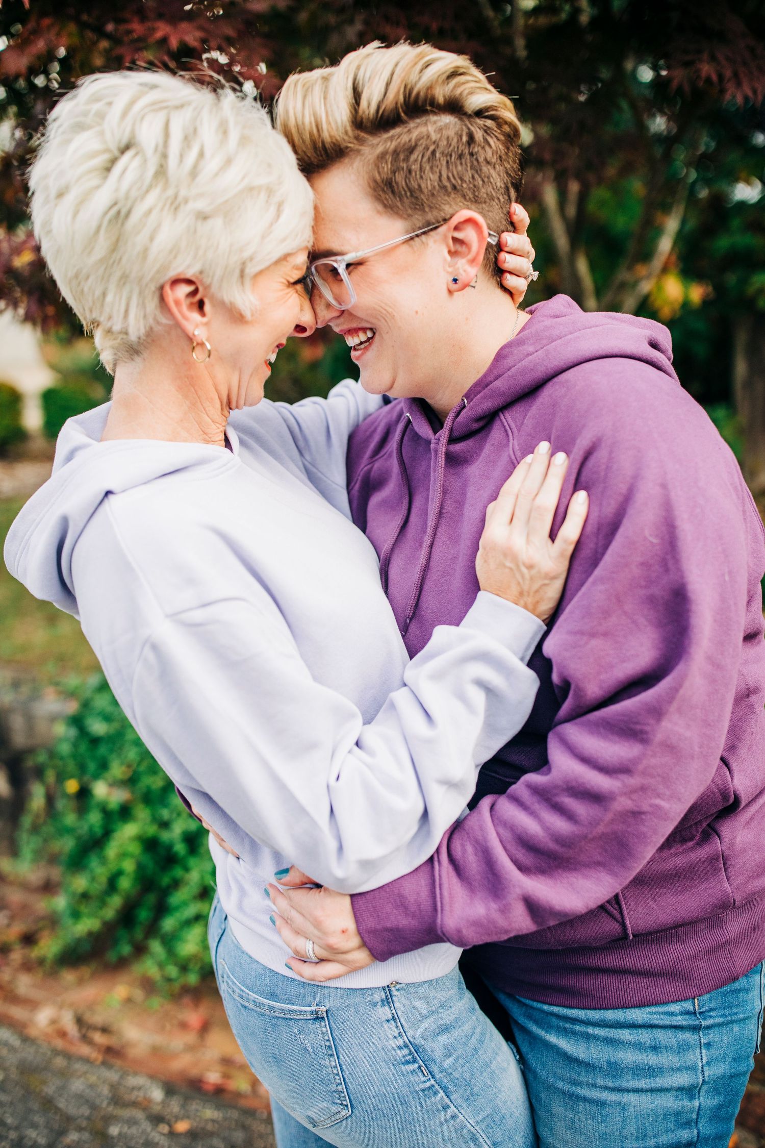 A tender moment between a couple embracing while wearing casual hoodies and jeans.