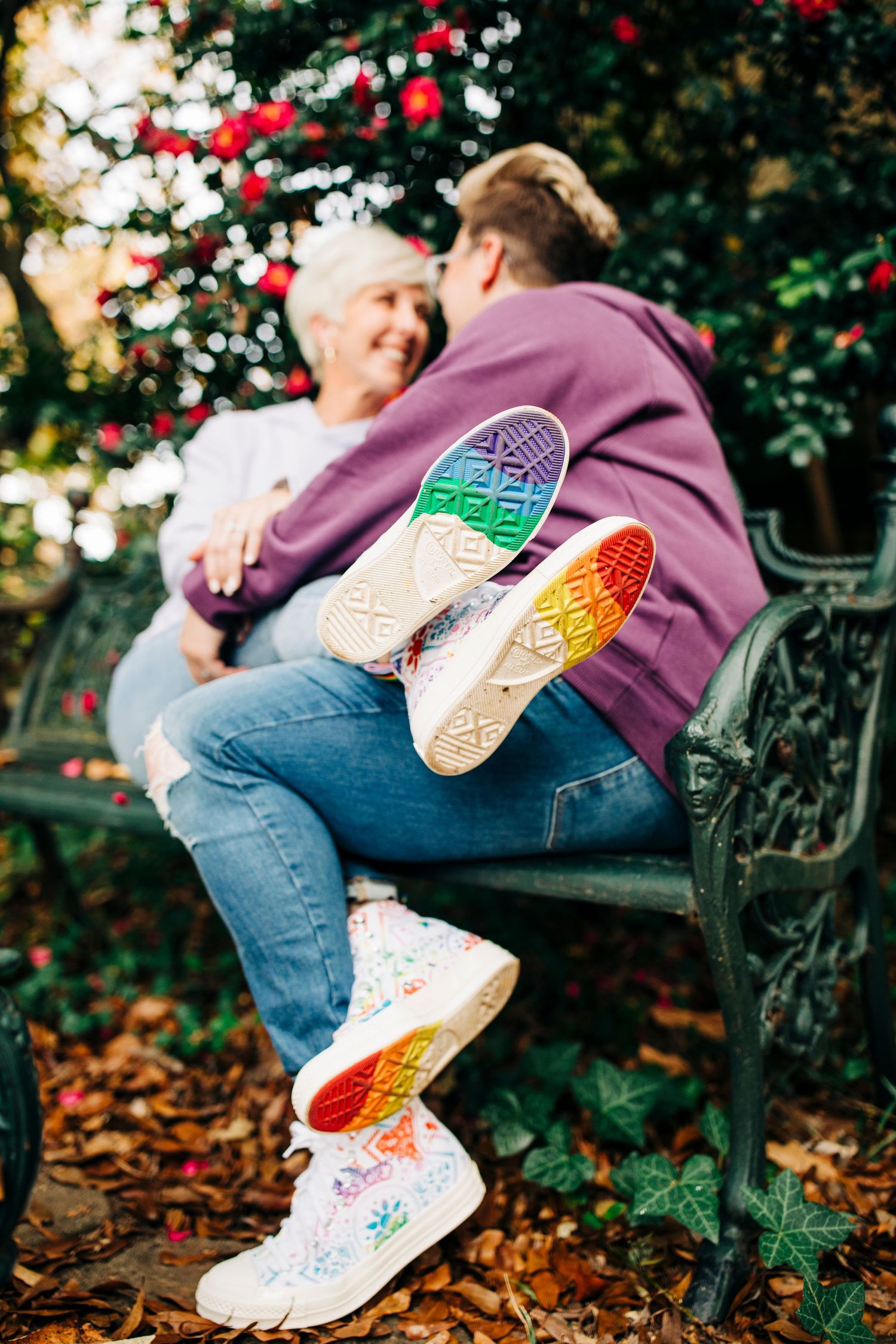 Close-up of colorful rainbow sneaker soles as couple sits on garden bench.