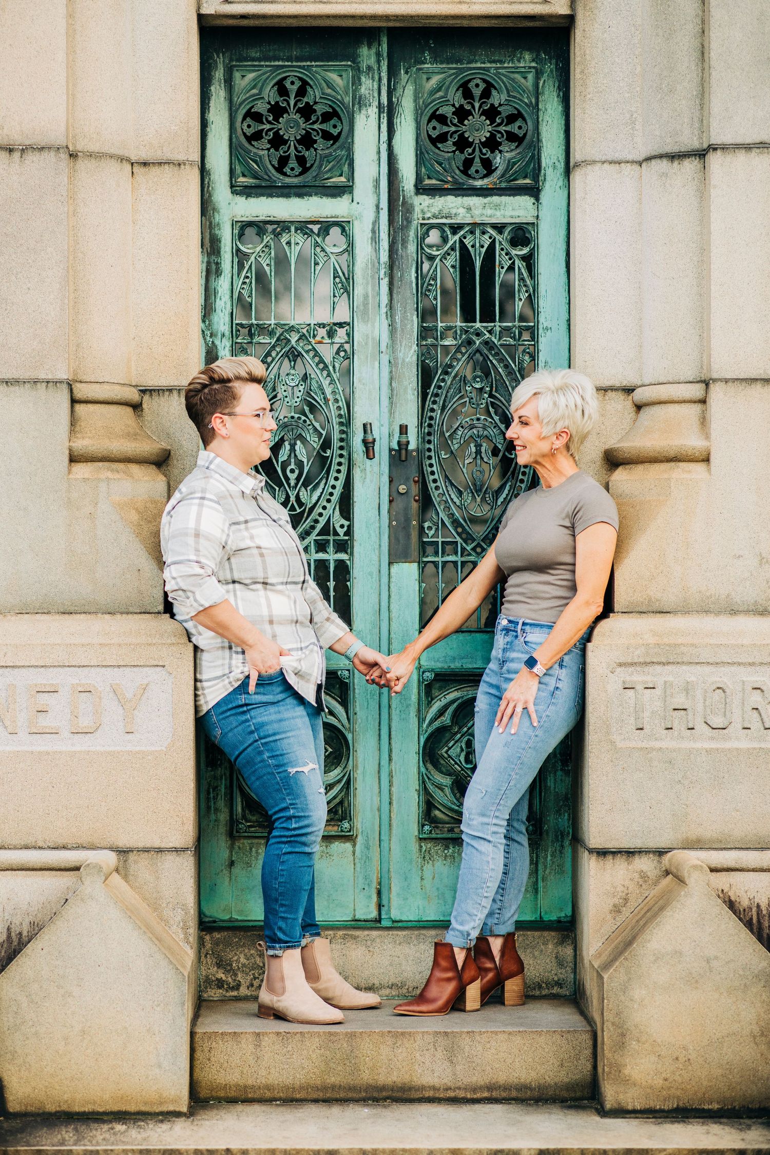 Couple posing in front of ornate turquoise doors wearing casual denim outfits.