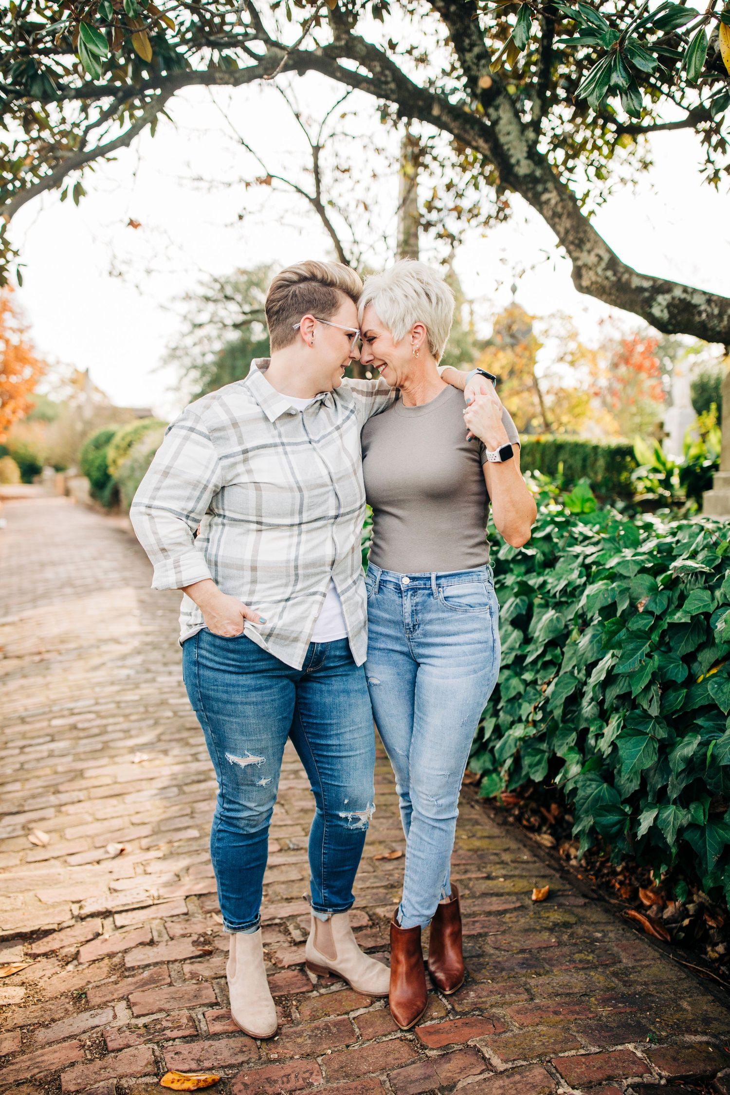 Romantic couple moment on brick pathway with autumn foliage in background.