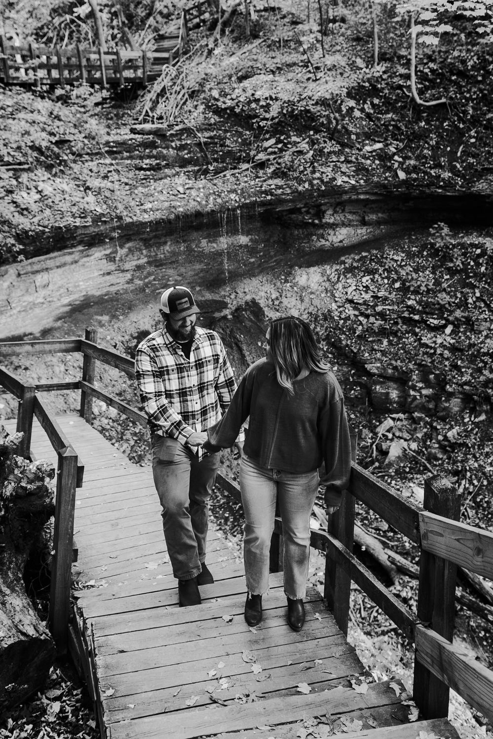 Woman leads man up walkway with waterfall in background