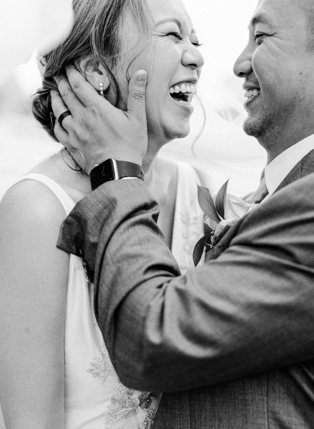 Black and white intimate portrait of a joyful wedding couple sharing a candid moment.