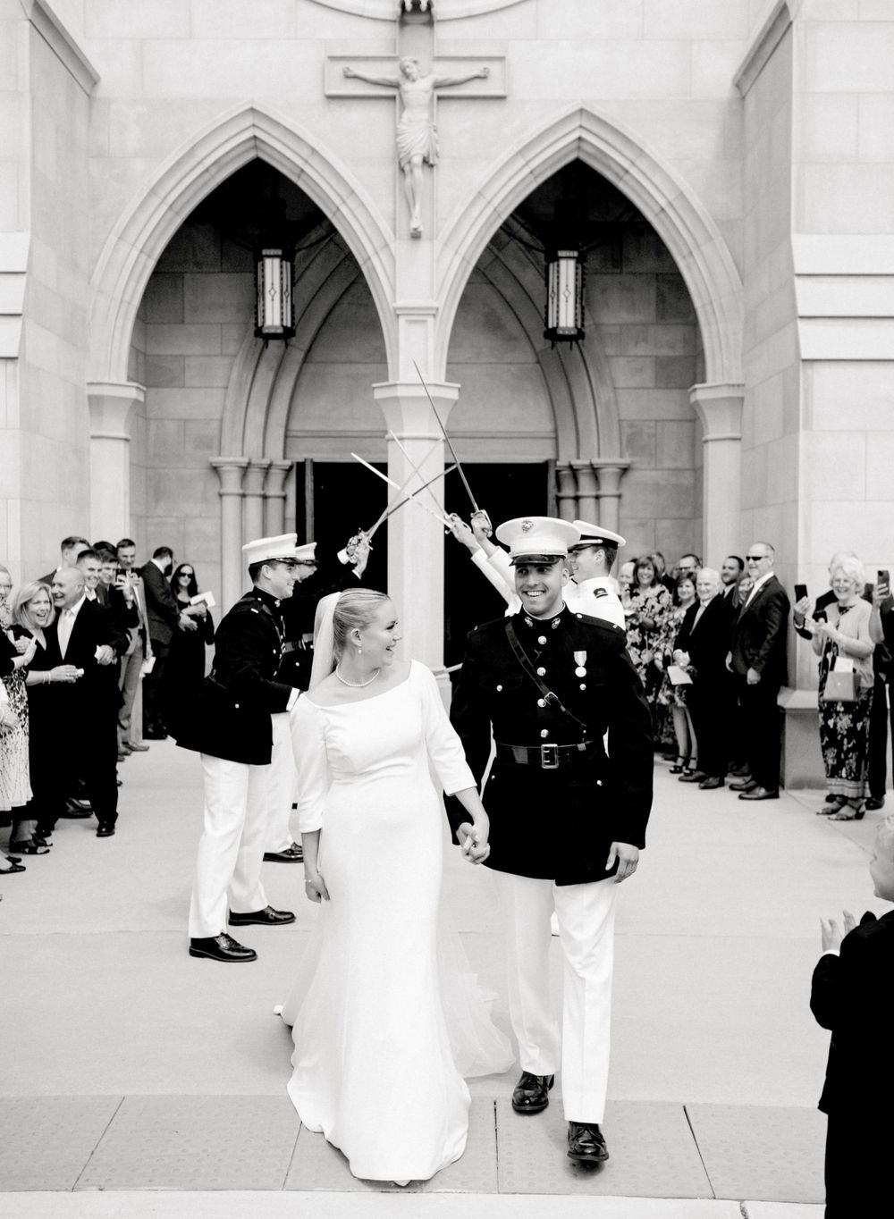 Military wedding ceremony under gothic arches with traditional sword arch and gathered guests.
