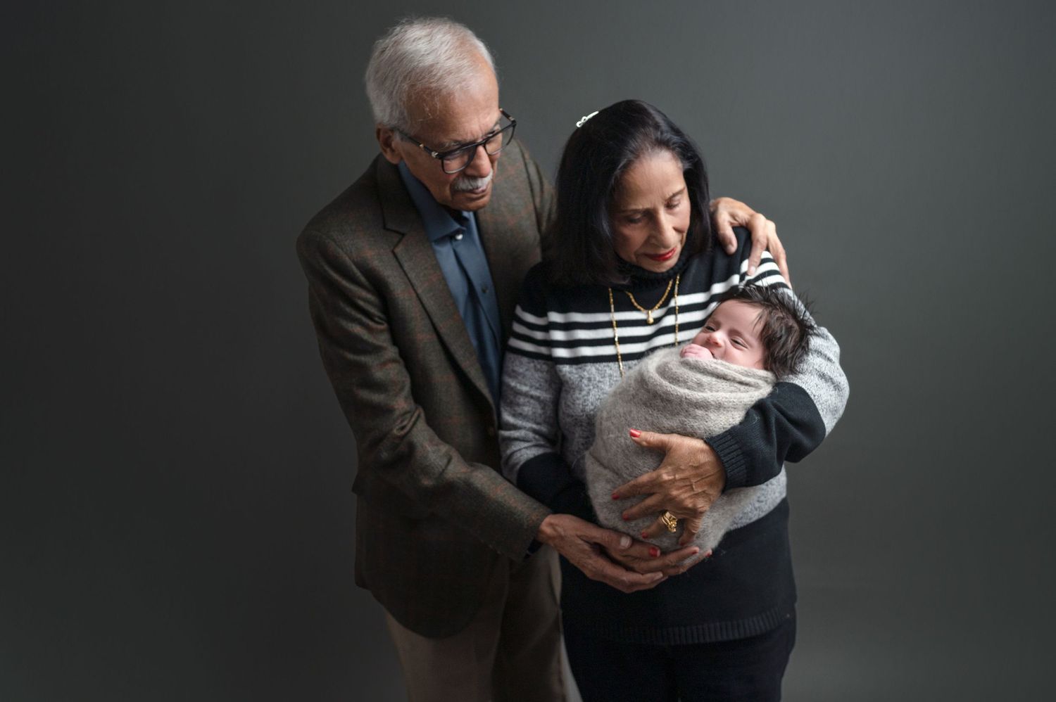 Dramatic black and white family portrait showing tender moment with baby.
