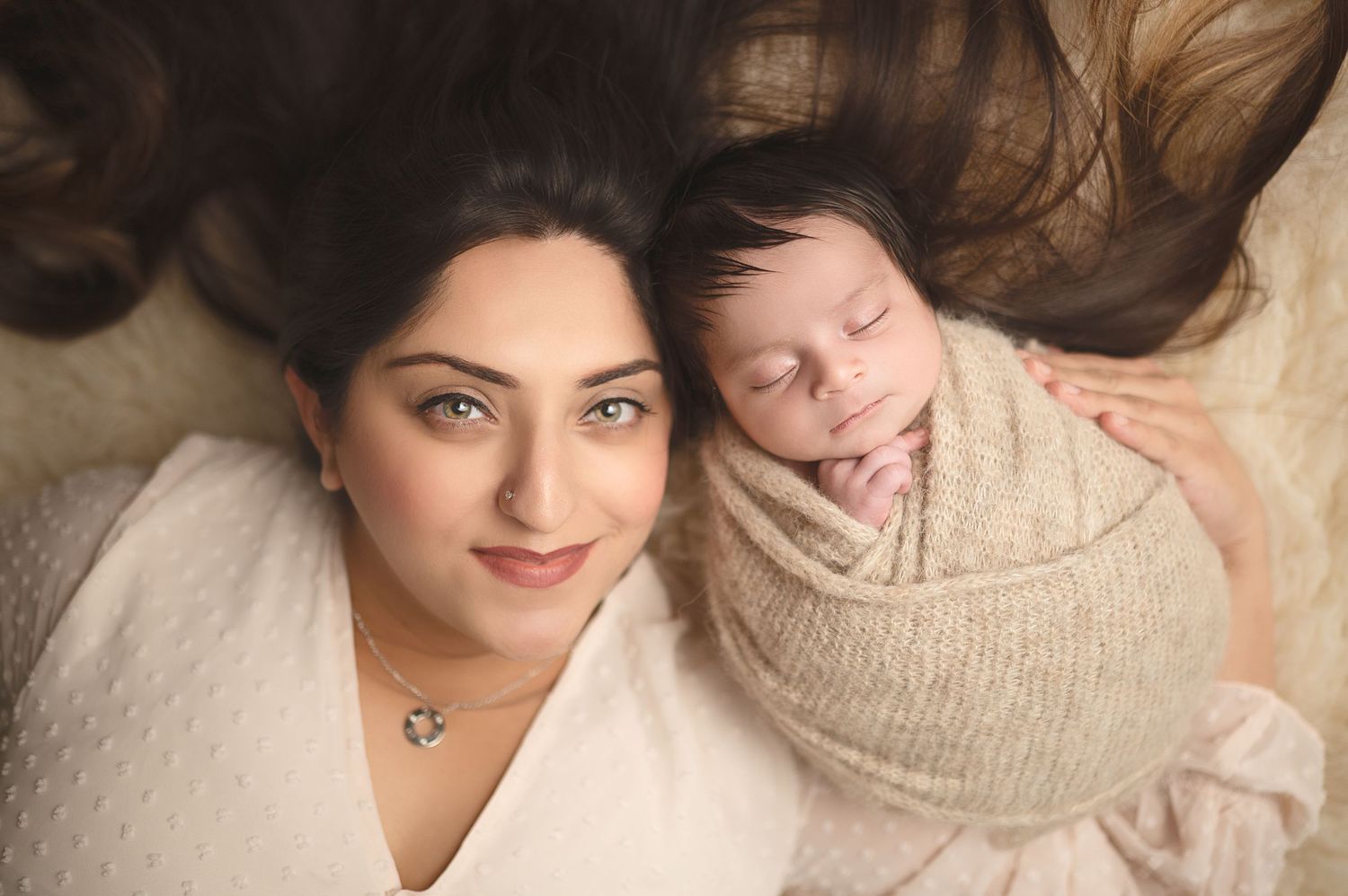 Overhead portrait of parent and sleeping newborn baby in neutral tones.