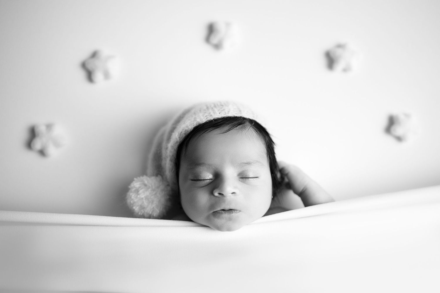 Artistic high-key newborn portrait with delicate butterfly decorations on white background.