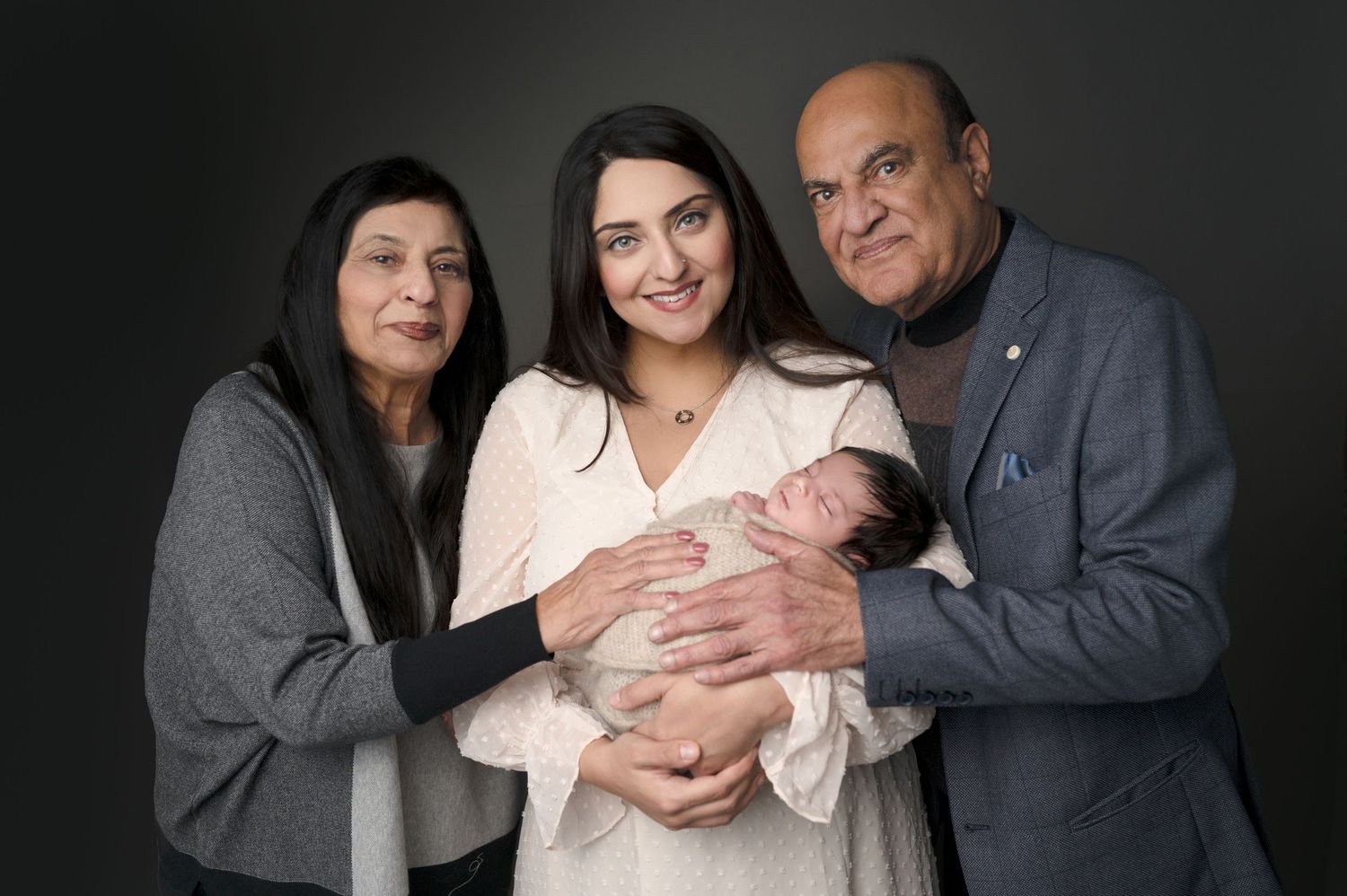 Professional family photography session with dramatic lighting against dark background.