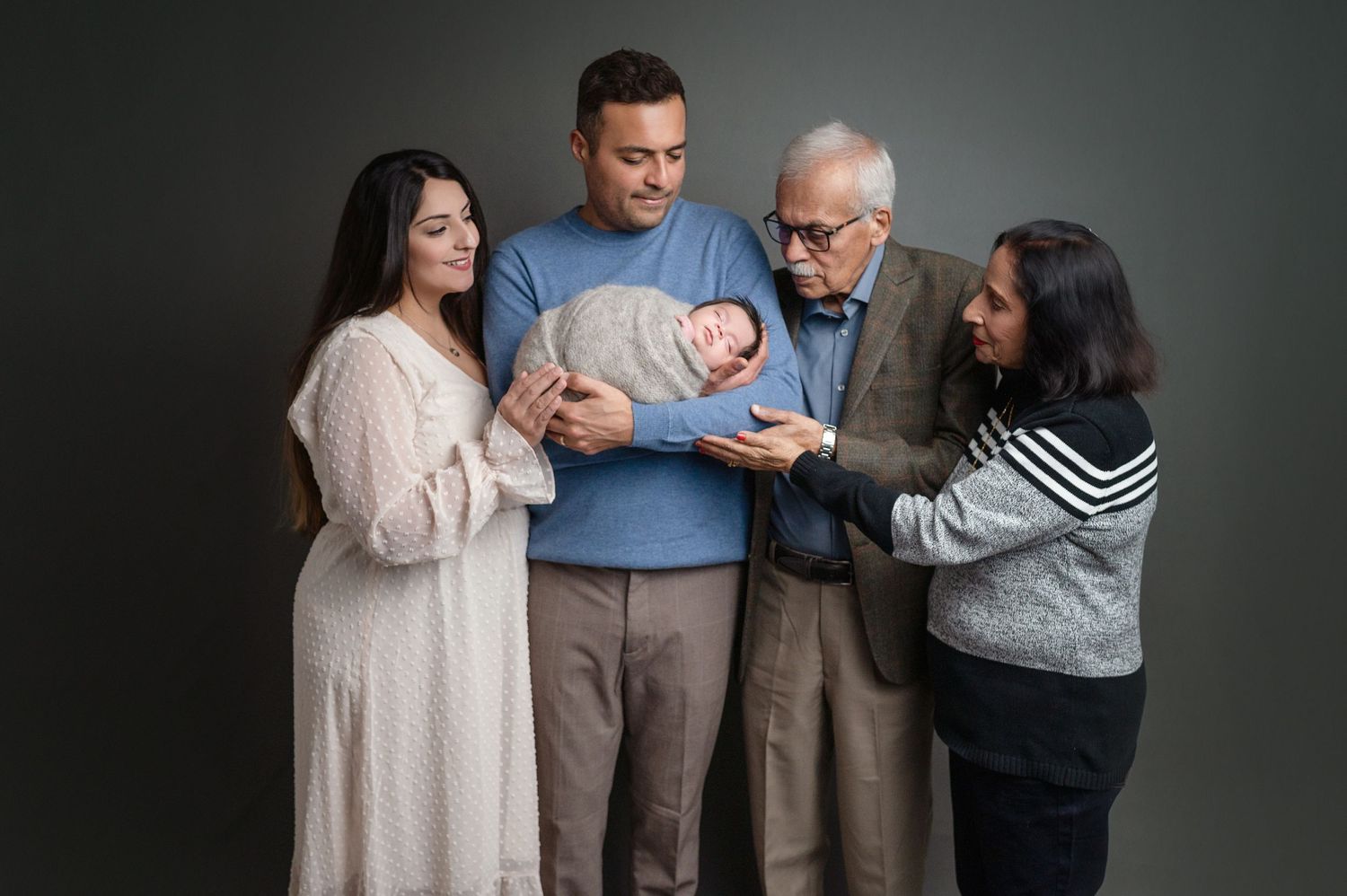 Multi-generational family photo session in studio with dark dramatic lighting.