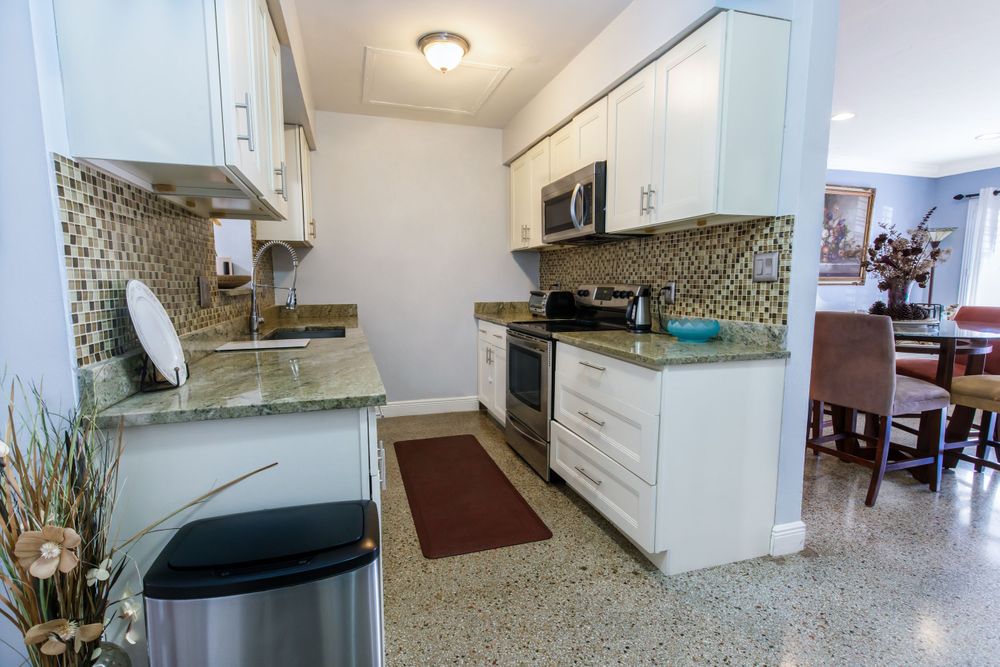 Open concept kitchen with mosaic tile backsplash and granite countertops extending into living space.