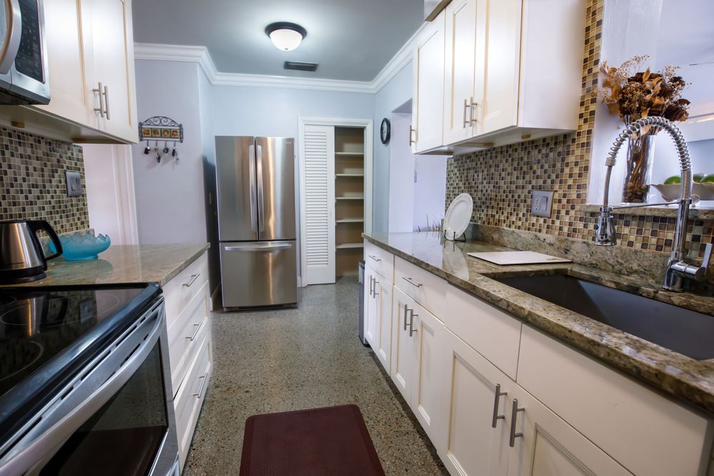White kitchen with stainless steel appliances, granite countertops, and ample cabinet storage.