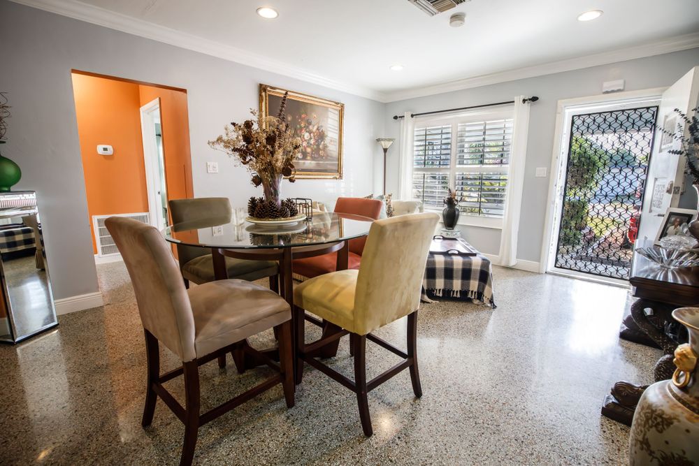 Modern dining area with orange accent wall, upholstered chairs, and decorative centerpiece.
