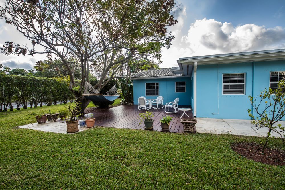 Wide angle view of a bright blue house with tropical landscaping and palm trees.