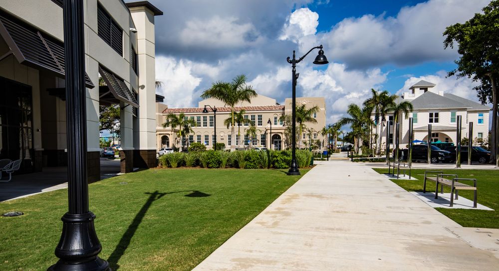 Wide concrete walkway lined with palm trees and street lamps on a sunny day.