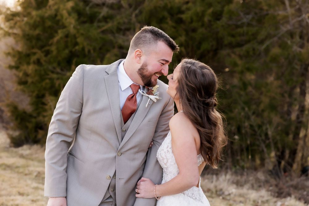A romantic outdoor portrait of newlyweds in formal attire sharing an intimate moment.