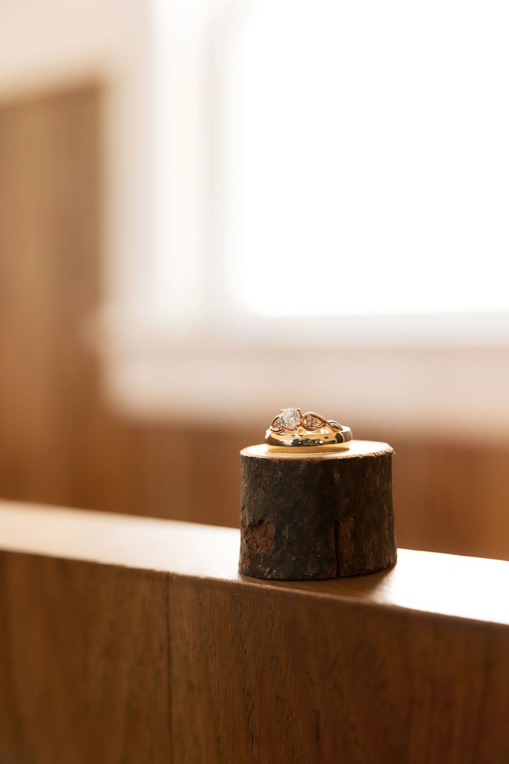 Wedding rings artistically placed on wooden surface in soft natural lighting.