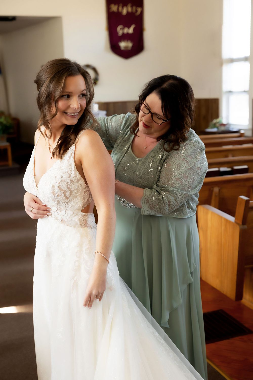Final dress adjustments being made in sunlit church interior.