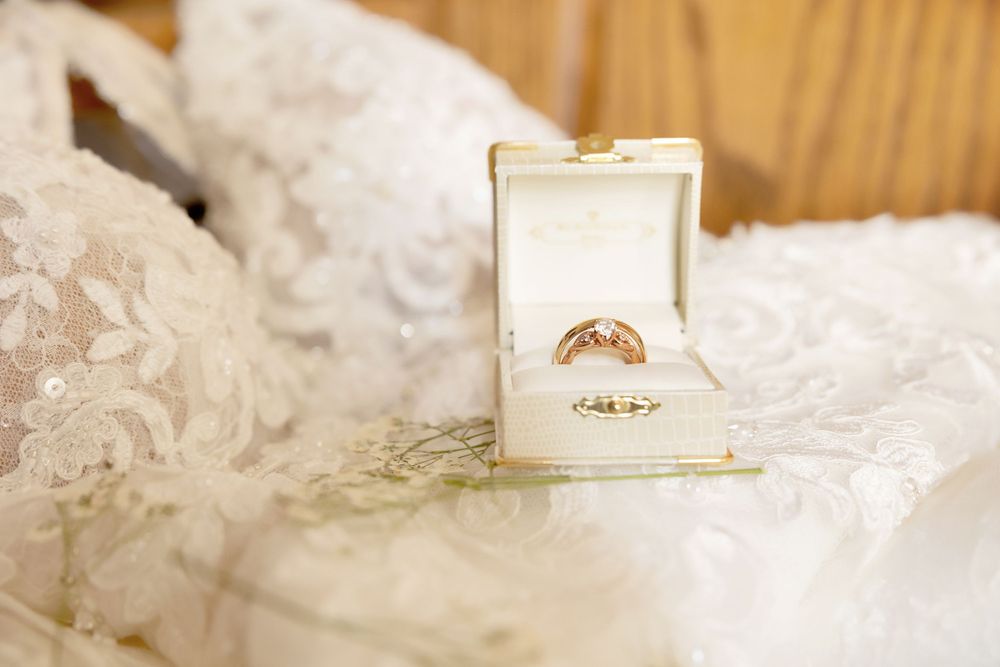 Wedding rings displayed in white ring box on lace fabric.
