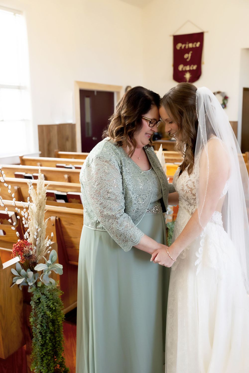 Intimate moment shared in church pew with floral decorations and burgundy banner visible.