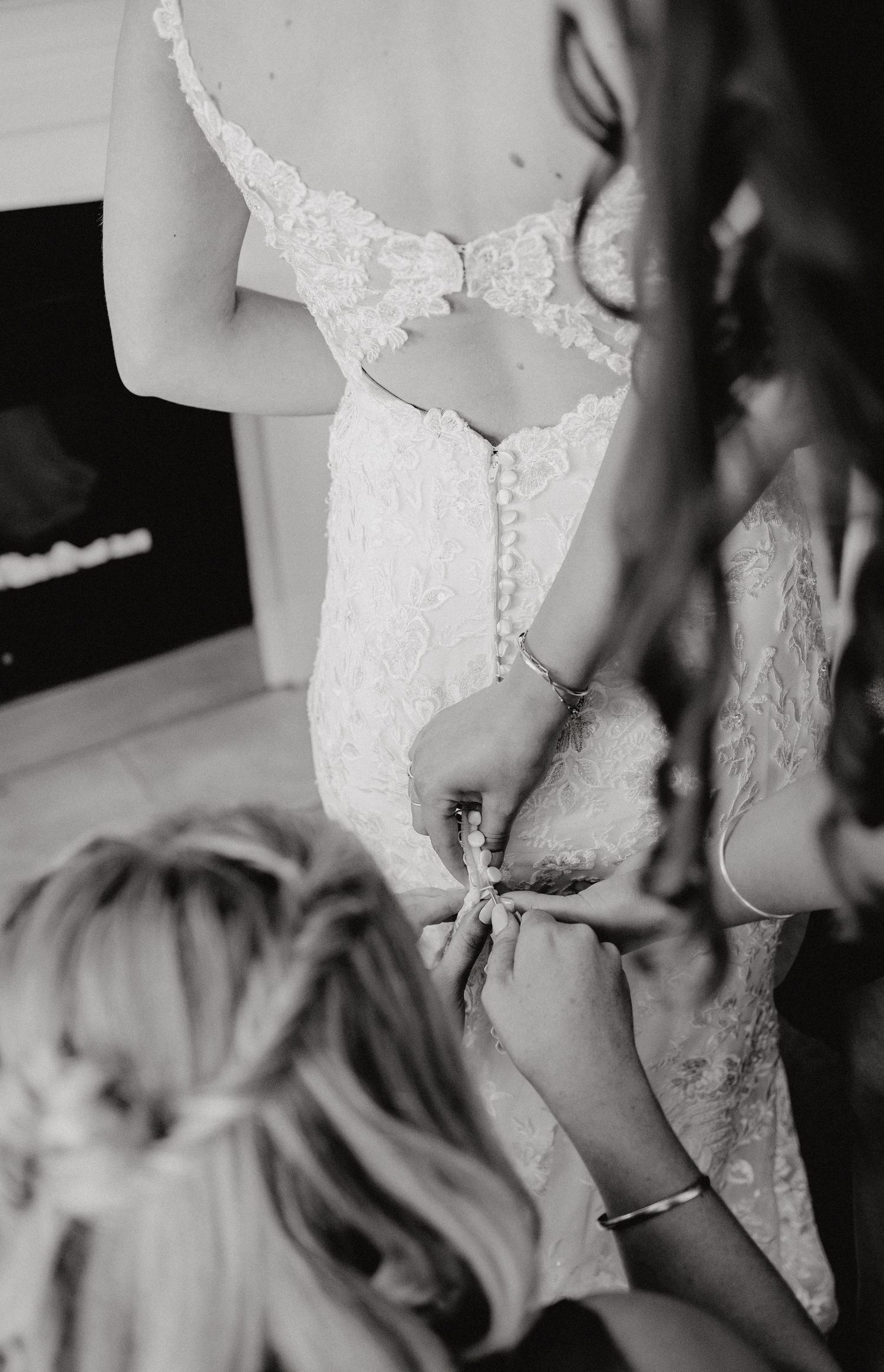 Black and white closeup photo of wedding dress lace details shows delicate beadwork and embellishments.