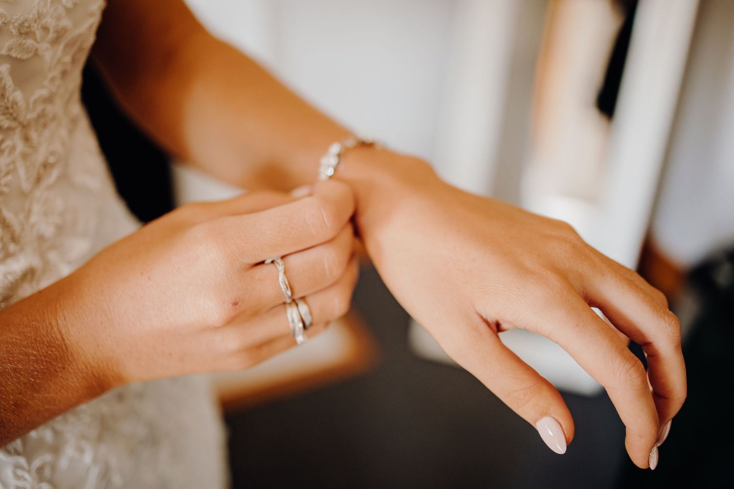 Close-up of elegant wedding rings being exchanged during ceremony against a light background.
