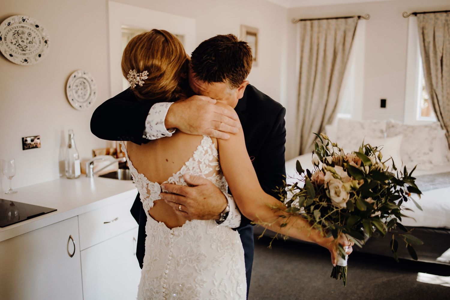 Emotional wedding day moments captured in a bright indoor setting with floral arrangements.
