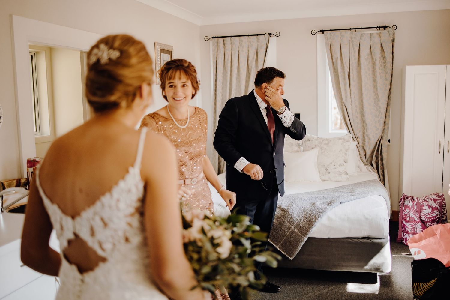 Wedding party members gathered in a light-filled room with white curtains and decor.
