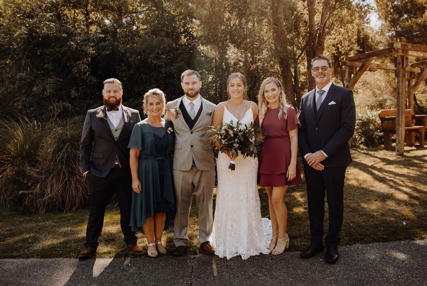 Wedding party poses together outdoors in coordinated formal attire.