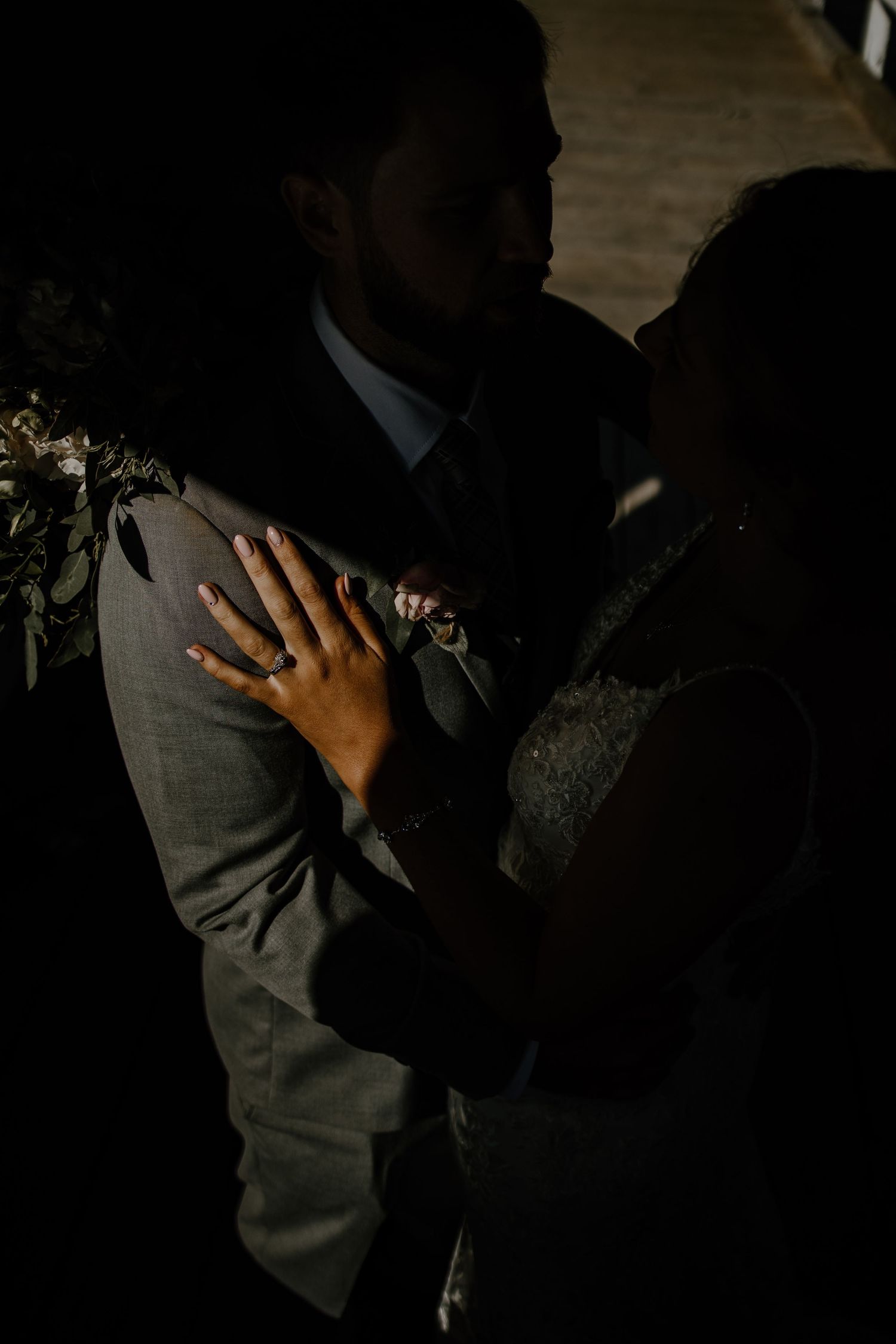 A dramatic silhouette of a couple embracing in formal wedding attire.