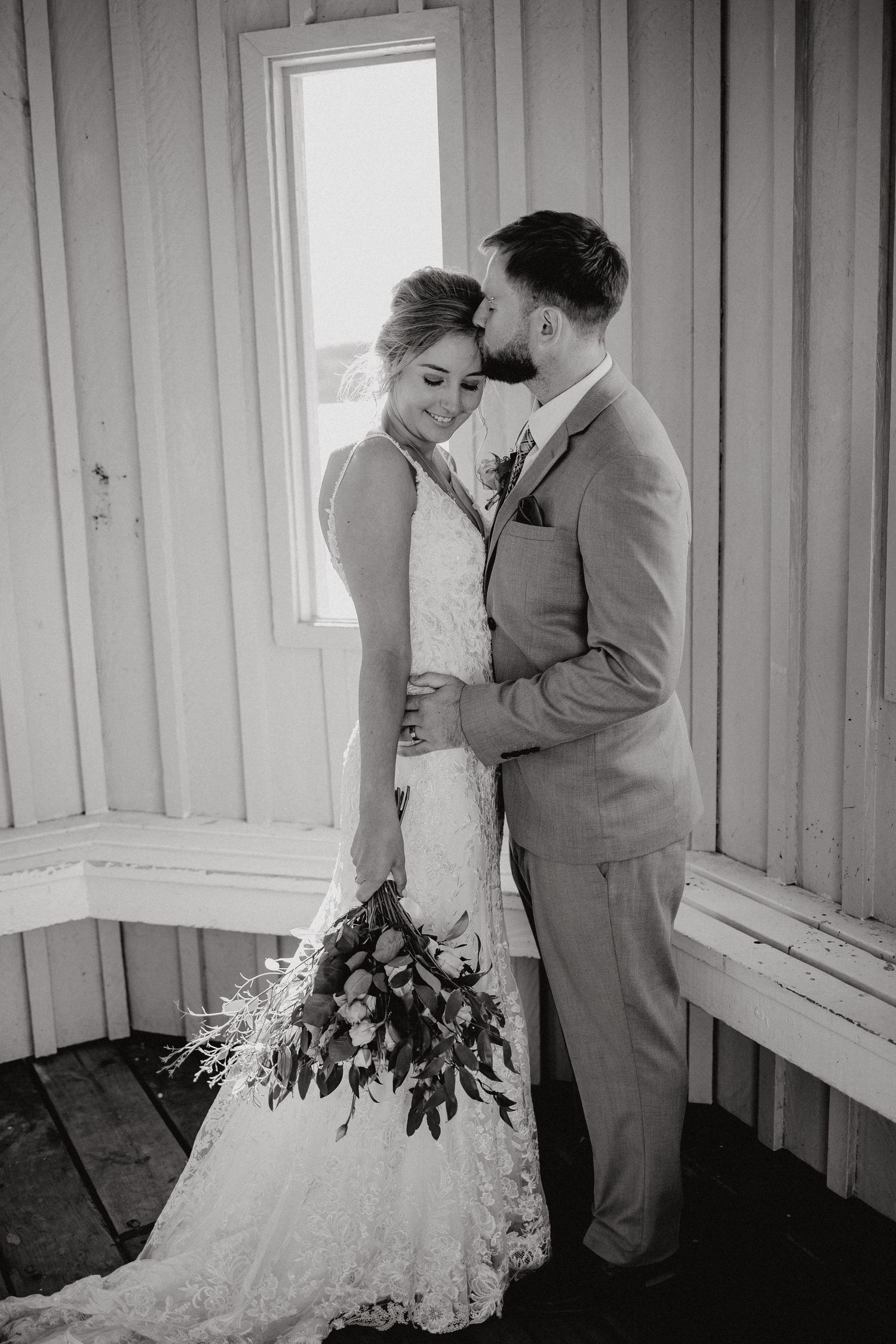 A tender black and white wedding portrait captured in front of a window.