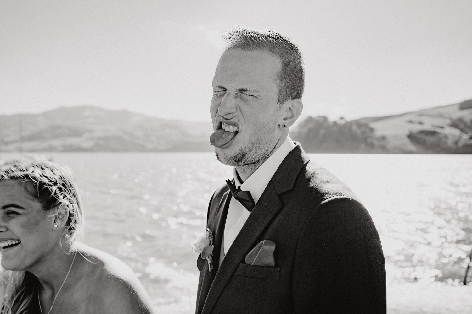 A candid black and white moment from a lakeside wedding celebration.