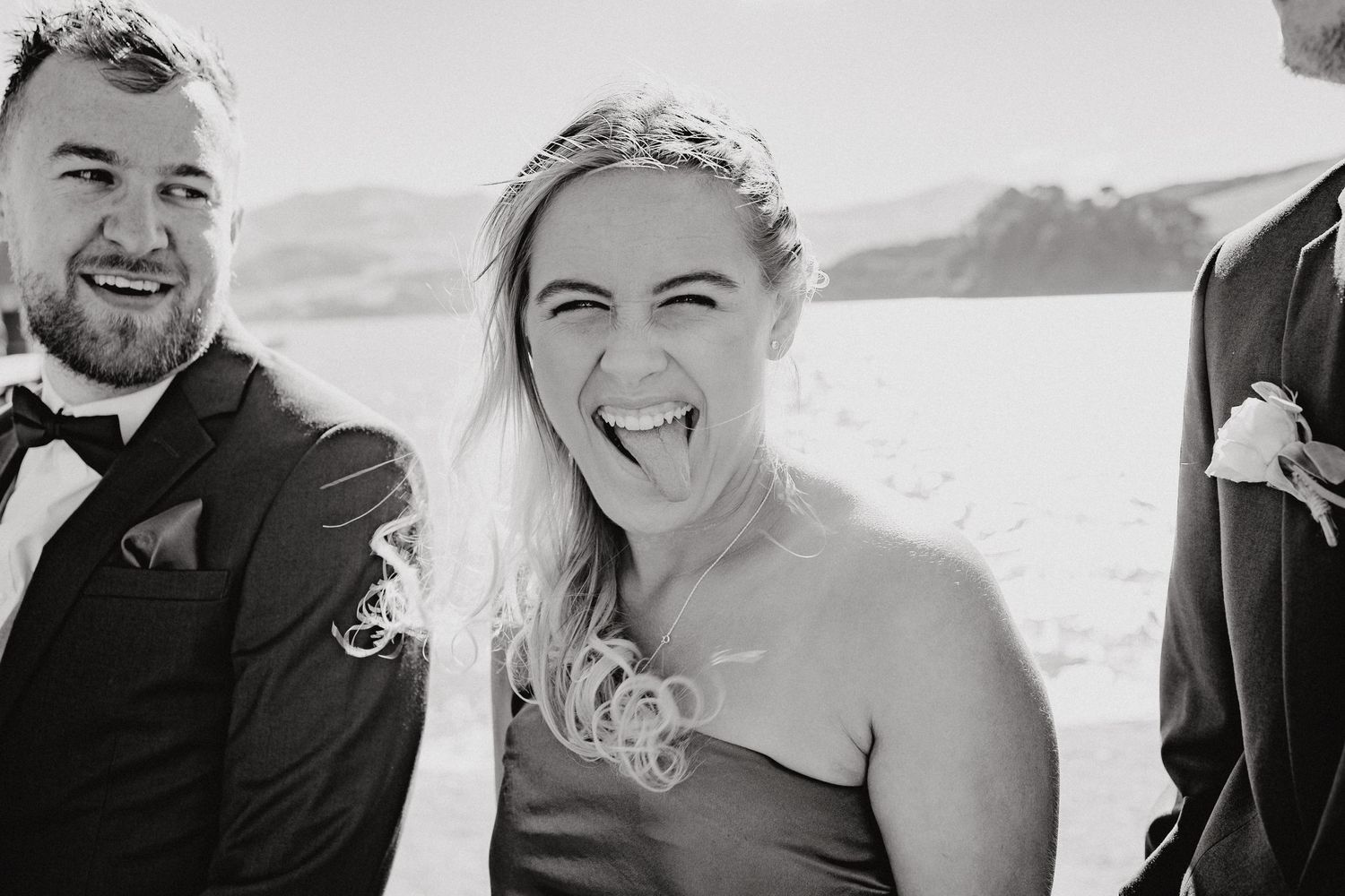 Black and white wedding photo showing joyful moments between couples at an outdoor celebration.