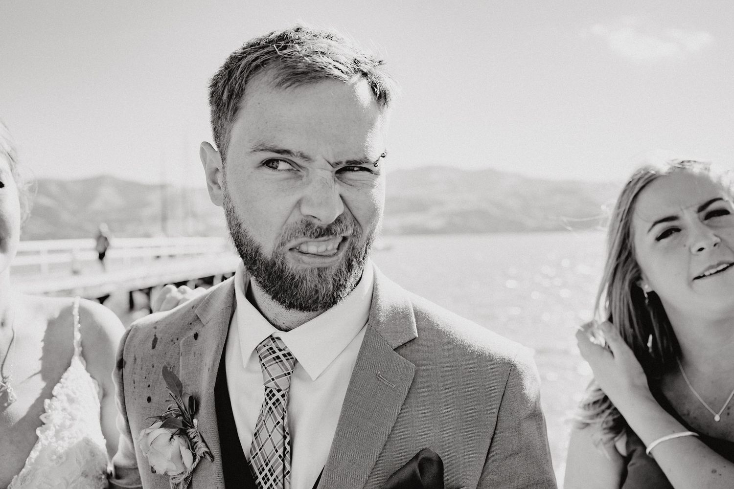 Wedding party members in formal attire photographed in black and white against mountains.