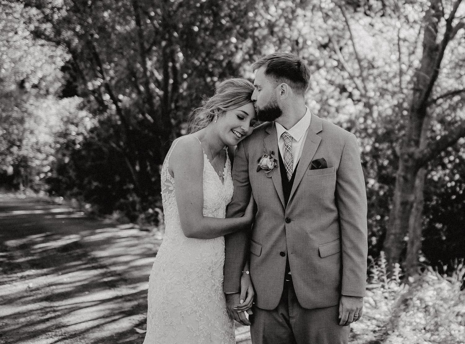 A tender embrace between newlyweds on a sunlit garden path.