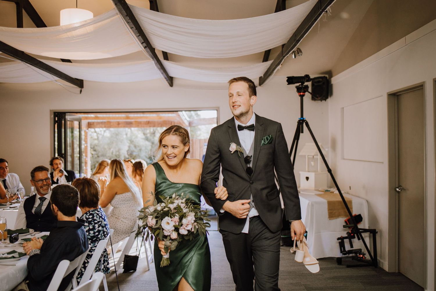 Newlyweds make their grand entrance into a modern reception venue with exposed beams.