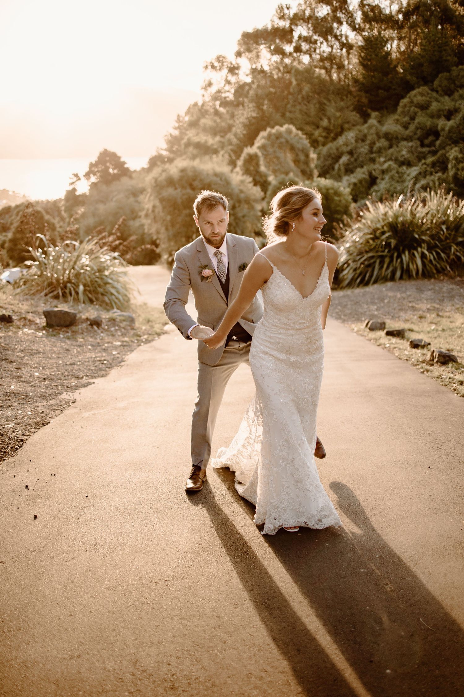 A couple walks along a sunlit path with ornamental grasses in the background.