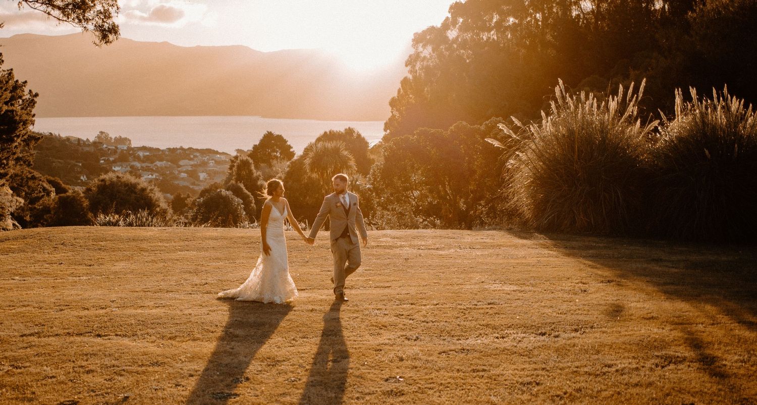 Silhouettes of newlyweds walking in a golden sunset with mountains in the background.