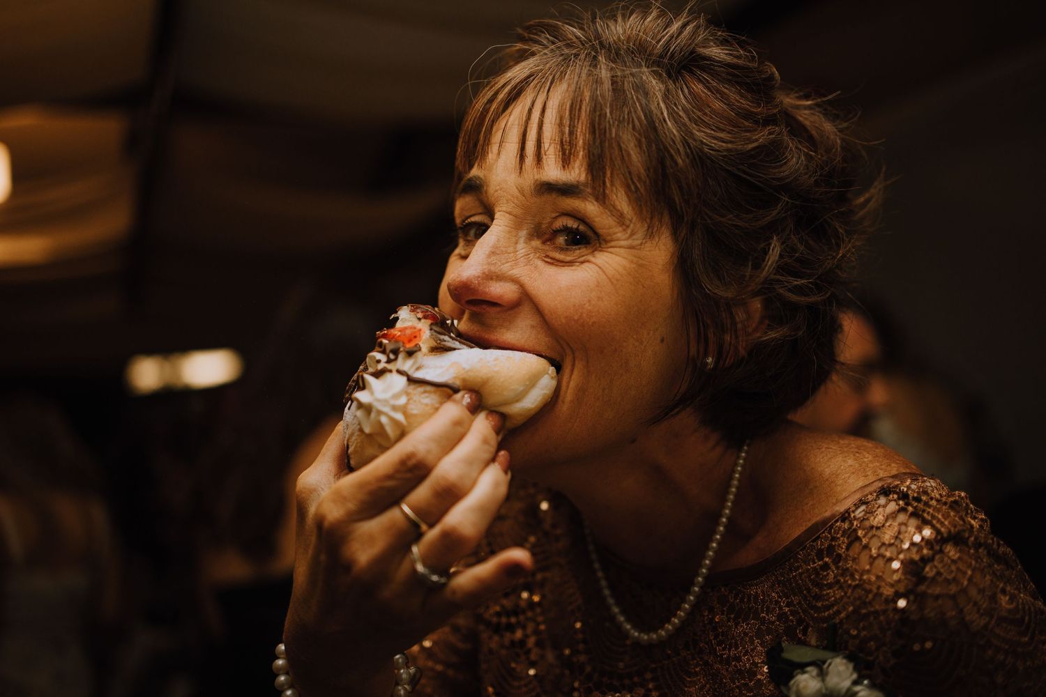 A celebration moment captured in warm lighting as dessert is being enjoyed at a wedding reception.