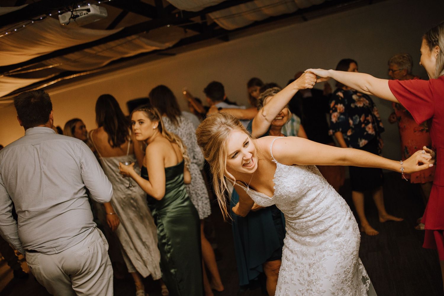 Lively dance floor scene at wedding reception with guests celebrating.