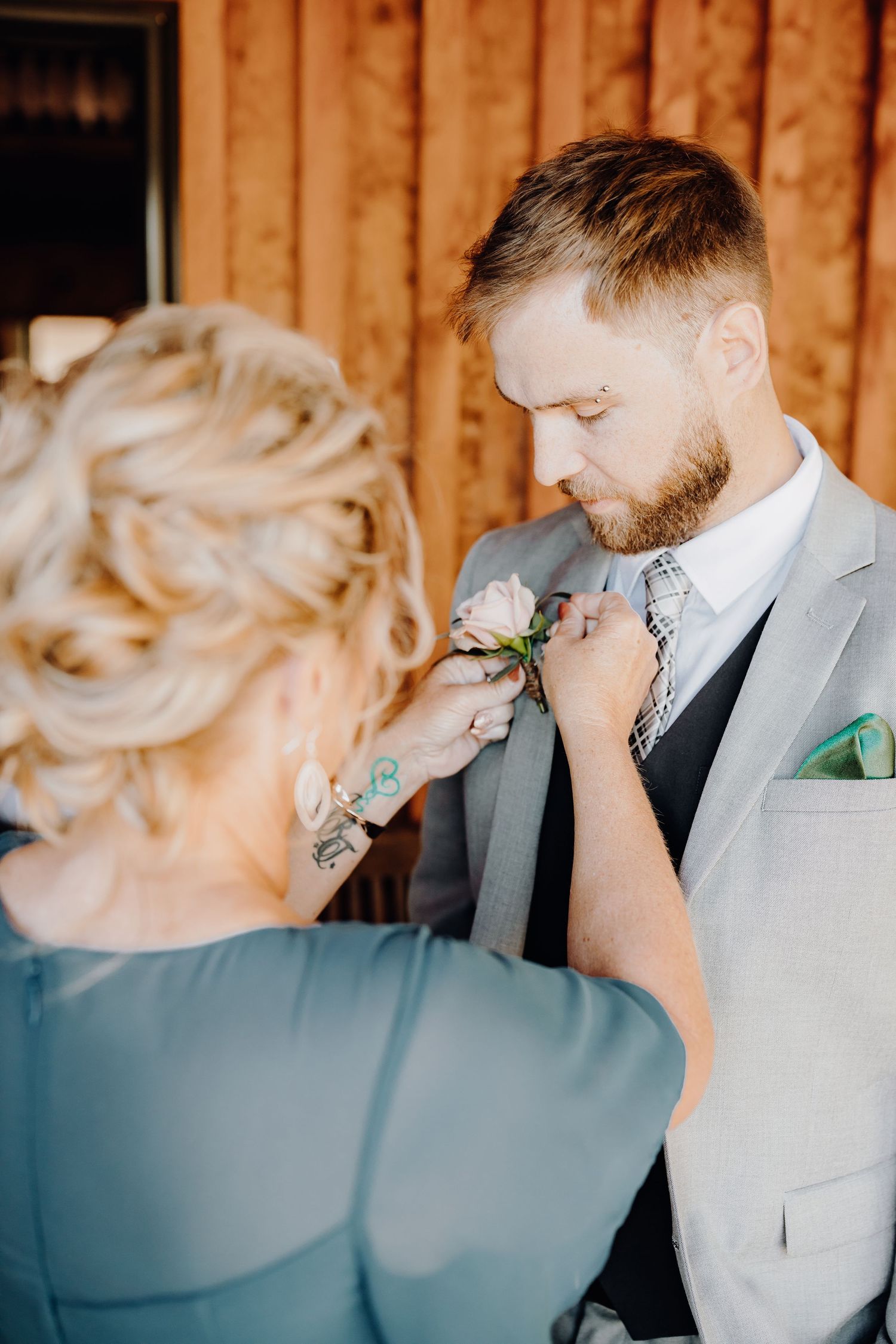 Intimate moment during wedding preparations as floral boutonniere is adjusted.