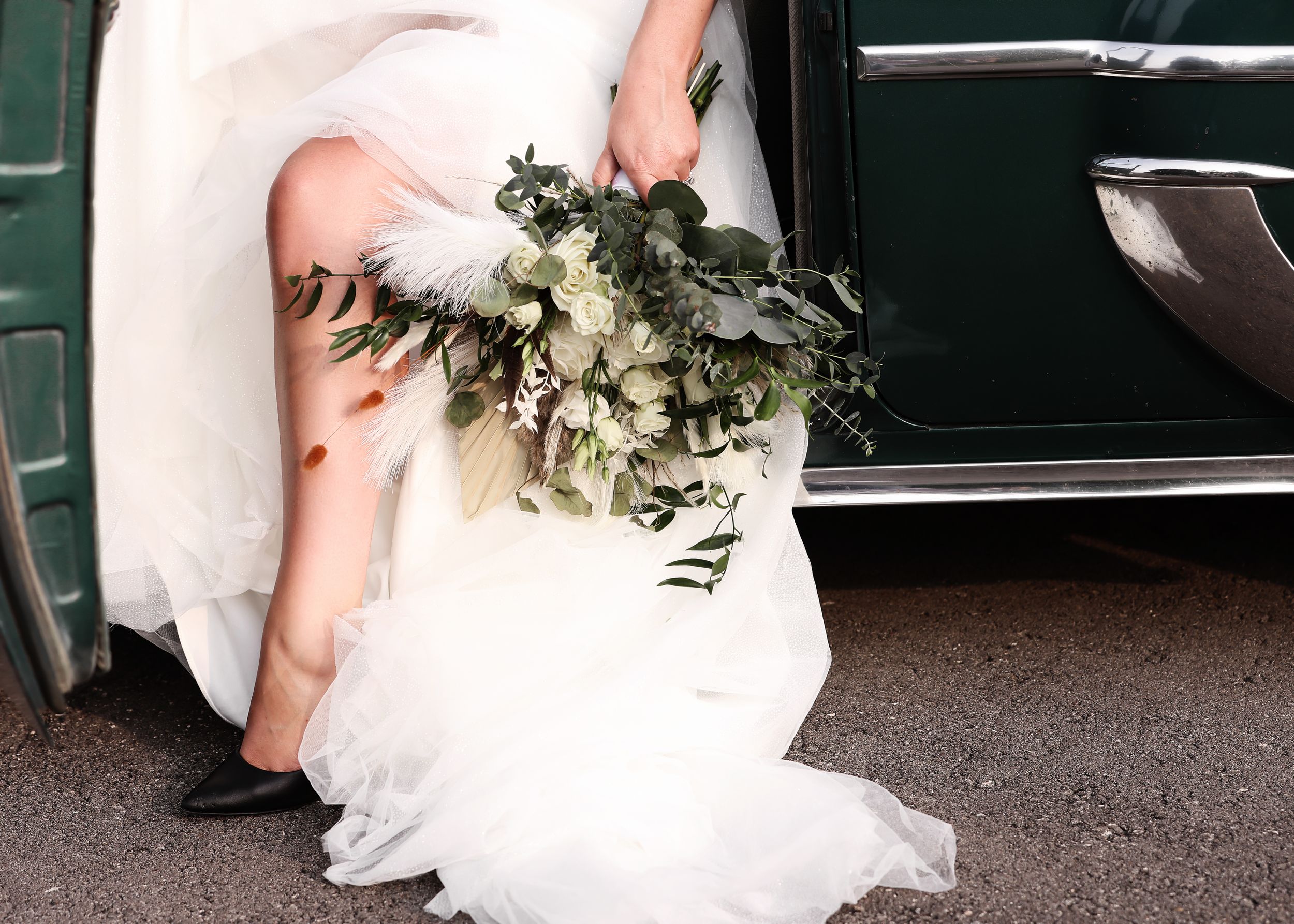 Wedding couple sitting together with white dress flowing on ground.