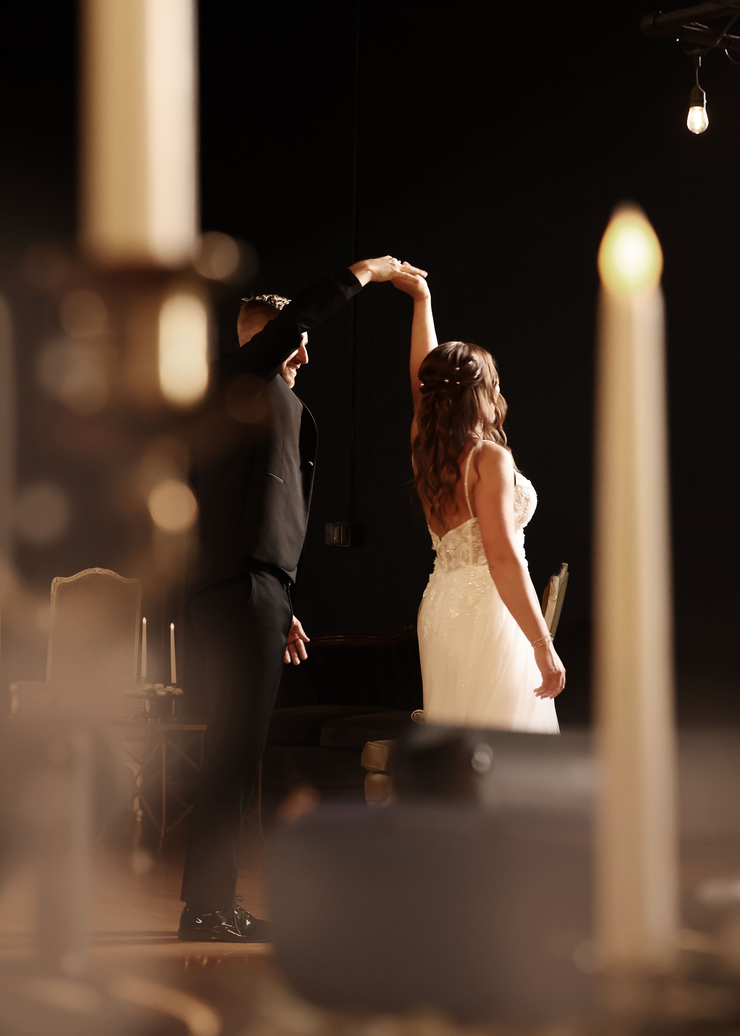 Silhouetted wedding couple dancing in dramatic venue lighting.