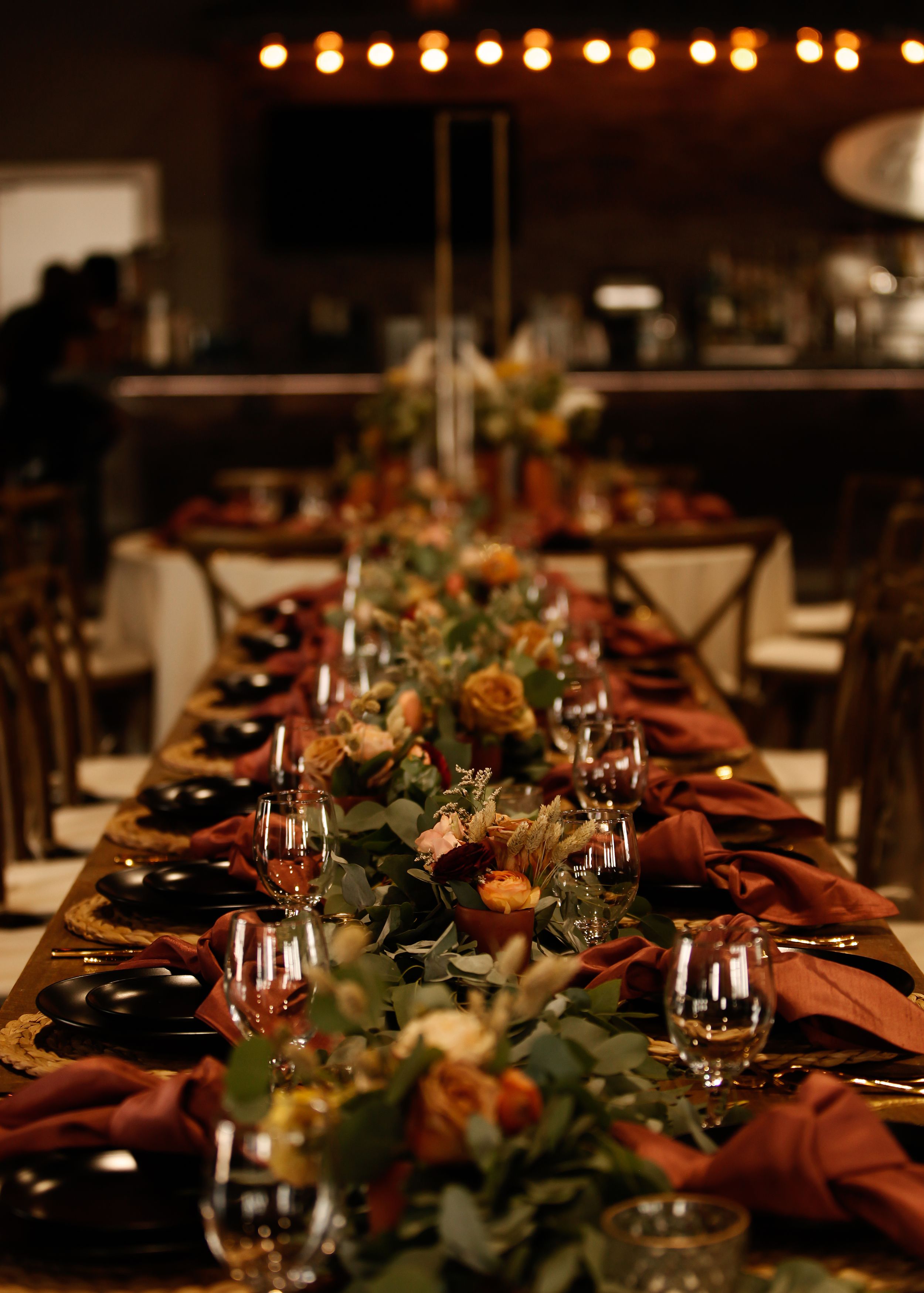 Elegant table setting with burgundy napkins and greenery at a formal event.