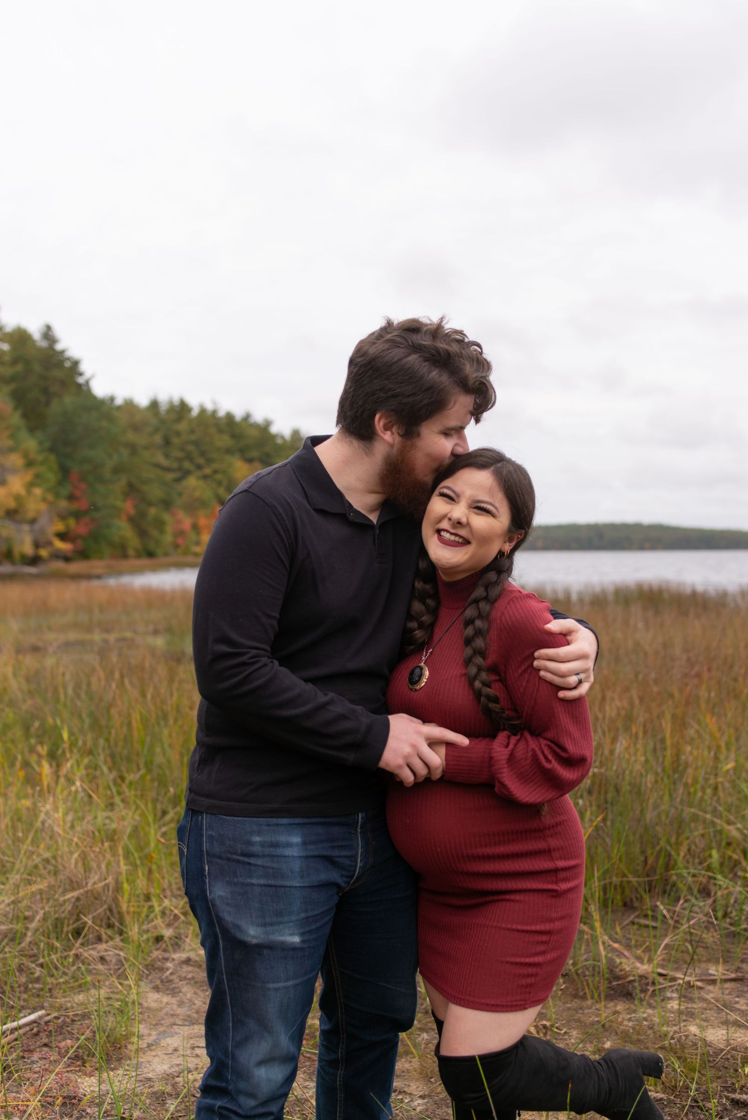 A couple shares a joyful moment together in a field during fall.