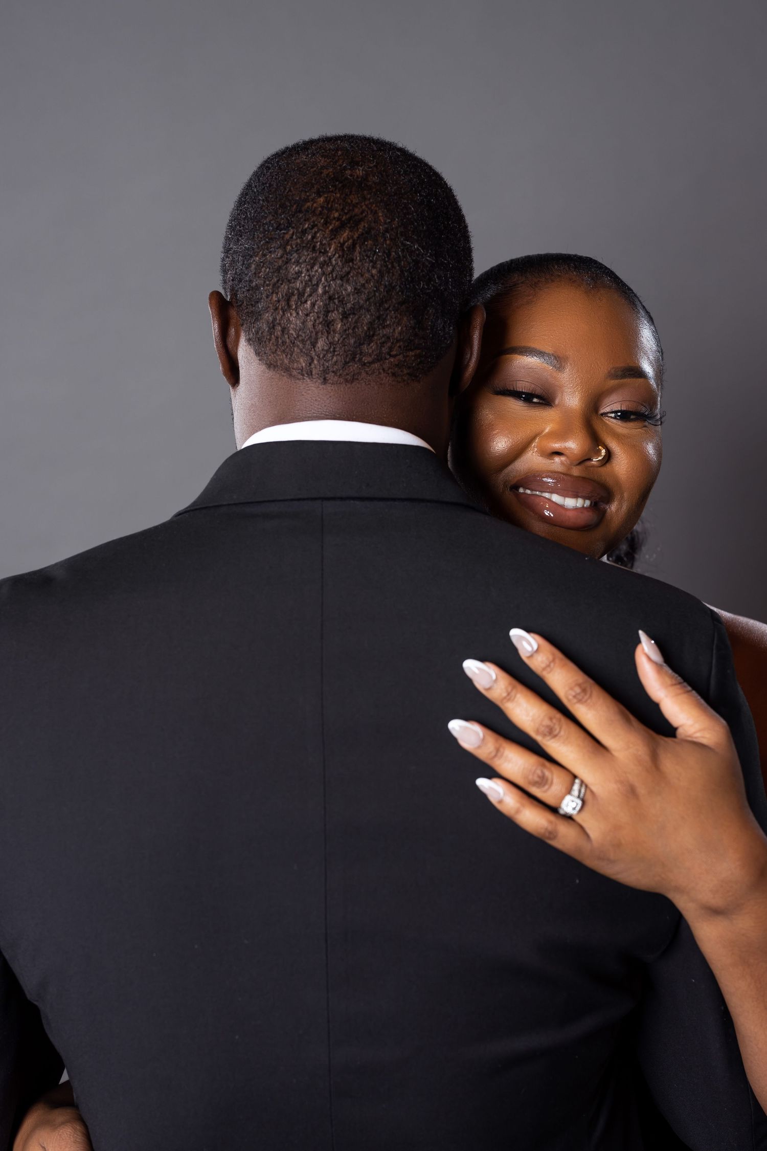 Intimate engagement photo showing ring display and emotional embrace.